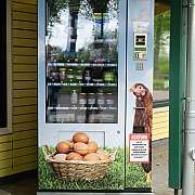 Verkaufsautomat mit Milchprodukten und Eiern vor gelbem Gebäude