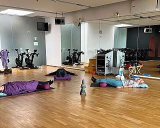 Teilnehmer liegen entspannt auf Matten in einem Fitnessraum.